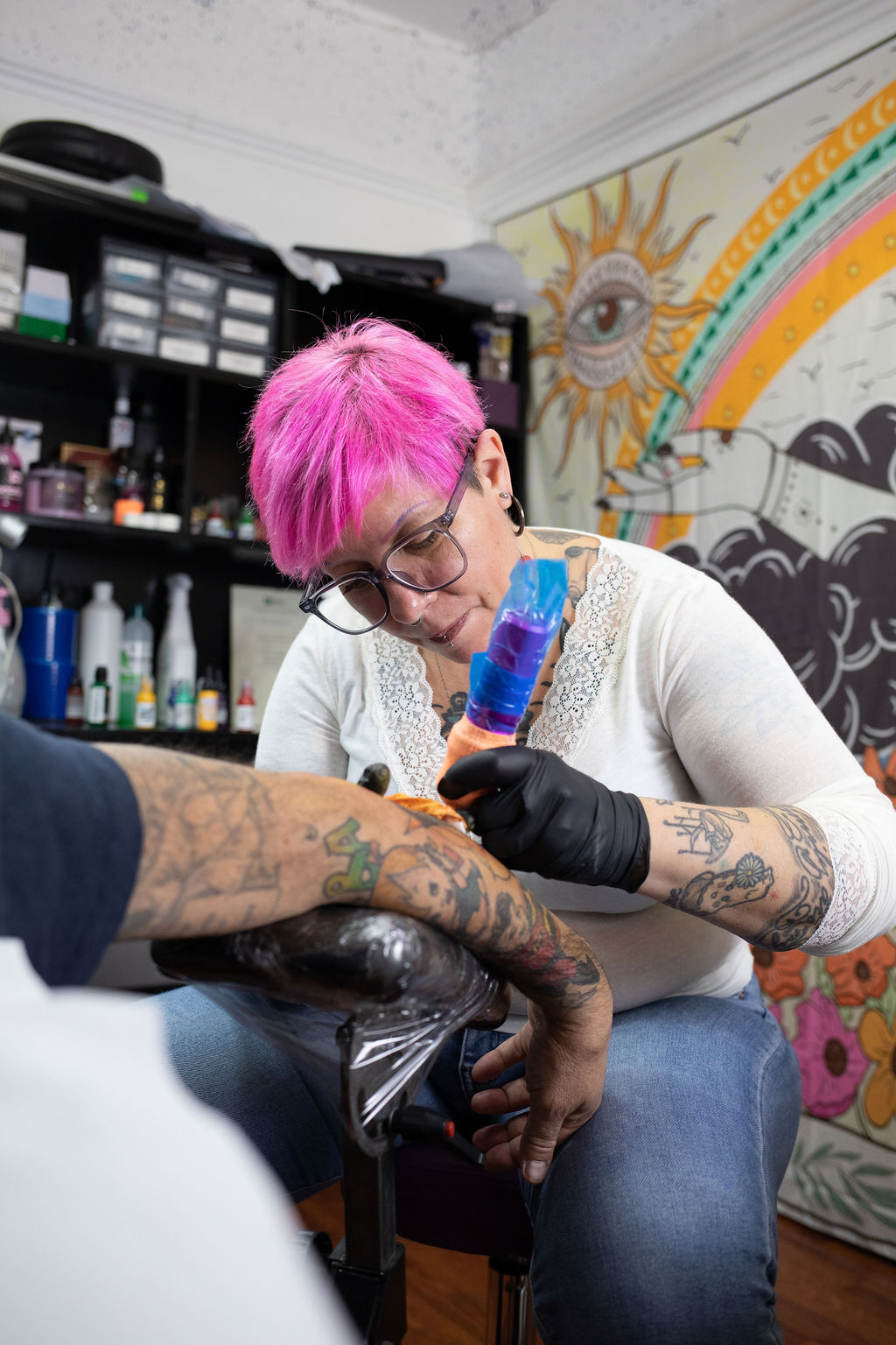 Una tatuatrice mentre tatua un braccio